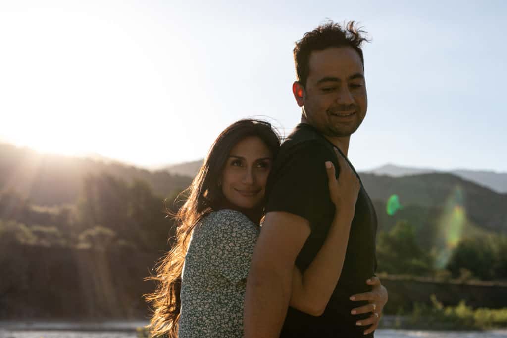 Un couple s'enlace au coucher du soleil. Photographe documentaire de mariage.