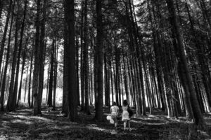 Deux amies de la future mariés en noir et blanc marchent au milieu de la forêt, lors Shooting photo EVJF, enterrement de vie de jeune fille, à La Croix d'Orval, dans la Vallée d'Azergues, près de Lyon. Photographie réalisée par Sabine Greppo, photographe de mariage à Lyon et partout en France. 