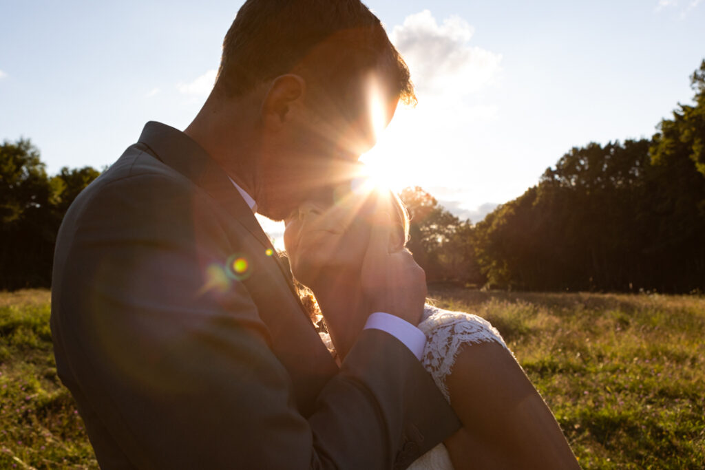 Un couple s'embrasse au coucher du soleil lors de leur shooting couple pendant leur mariage. Photo prise par Sabine Greppo, Photographe de mariage
