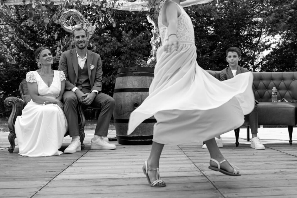 Une fille en robe blanche danse devant le couple lors d'une cérémonie de mariage laïque. Photo prise par Sabine greppo, photographe de mariage en France. 